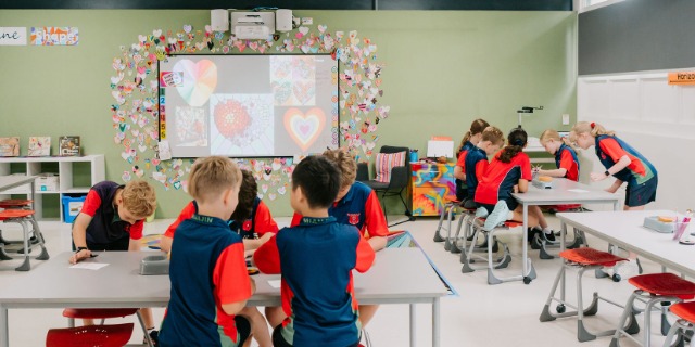 Students working at tables during a classroom learning activity.