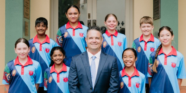 School staff member standing with a group of students in uniform.